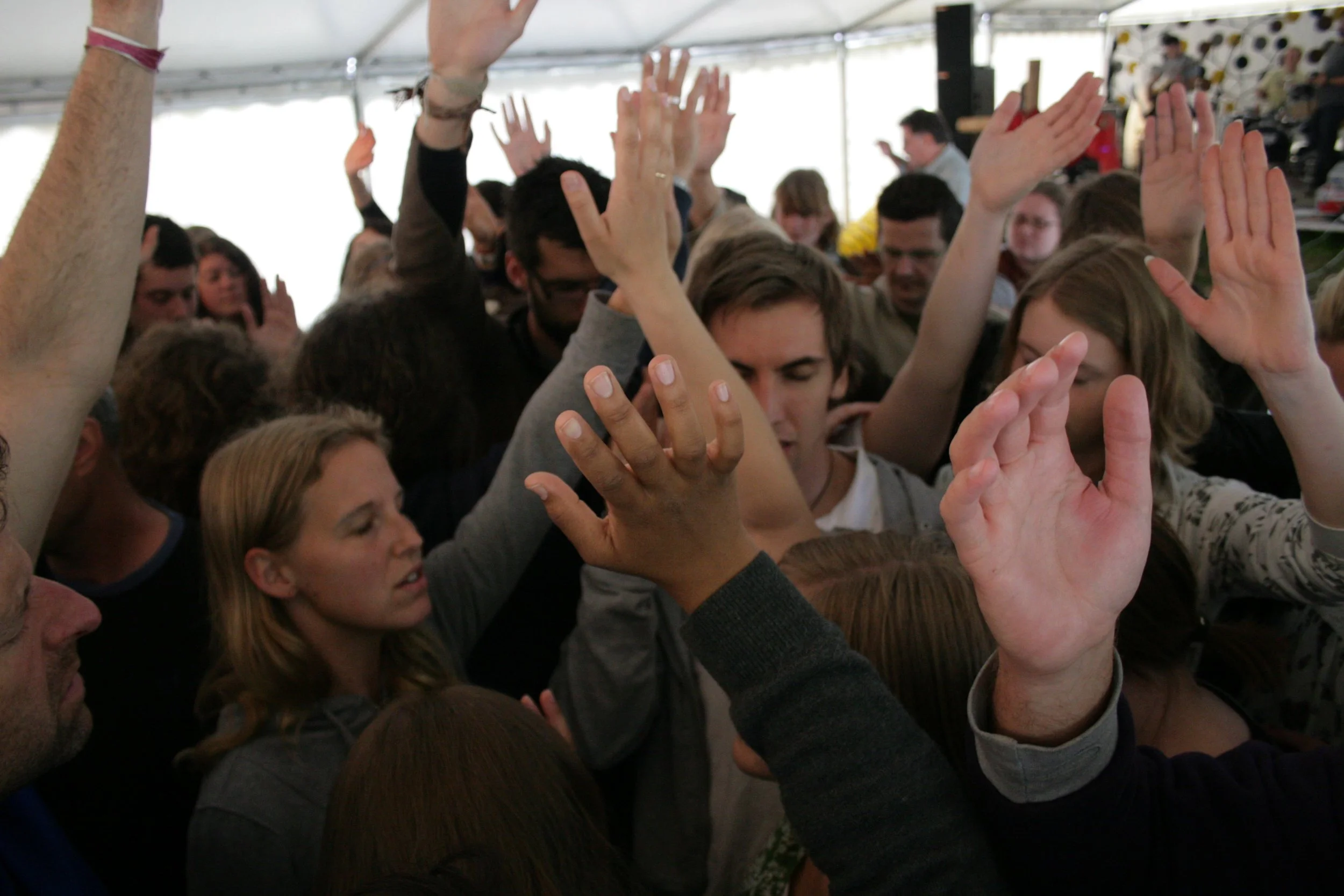 Crowd of people with hands raised, some touching or high-fiving, in a lively indoor space.