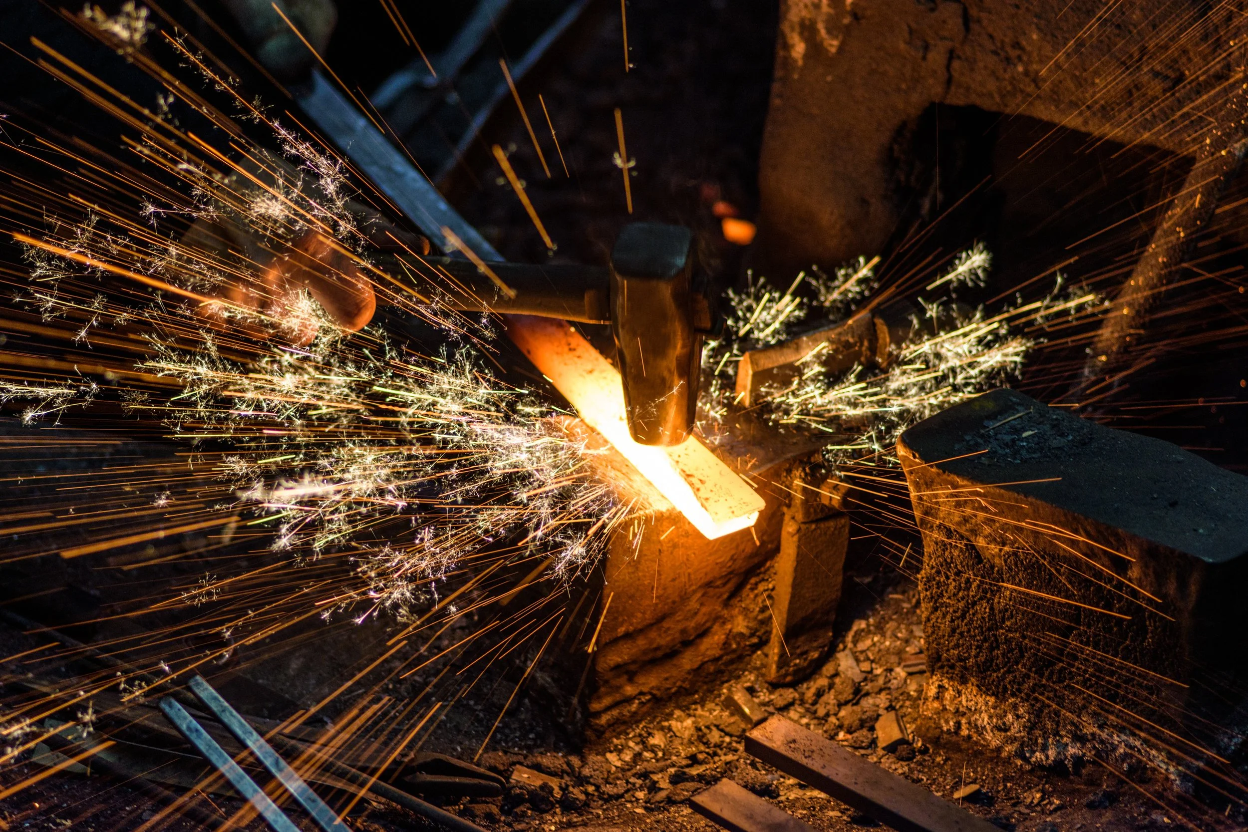 Metal being welded with sparks flying in various directions amid dark surroundings.