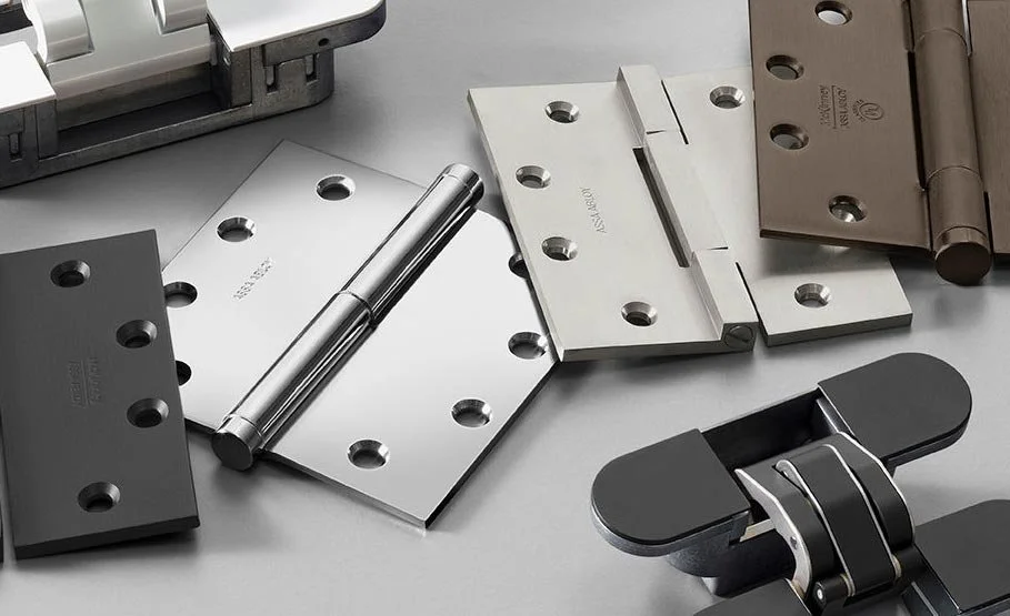 Assorted metal hinges and hardware parts on a gray surface.