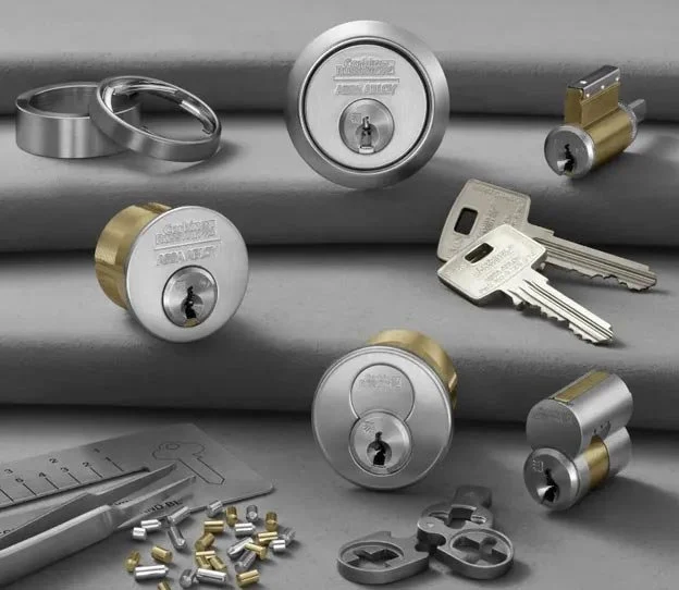 Various door locks, keys, and lock components arranged on a gray surface.