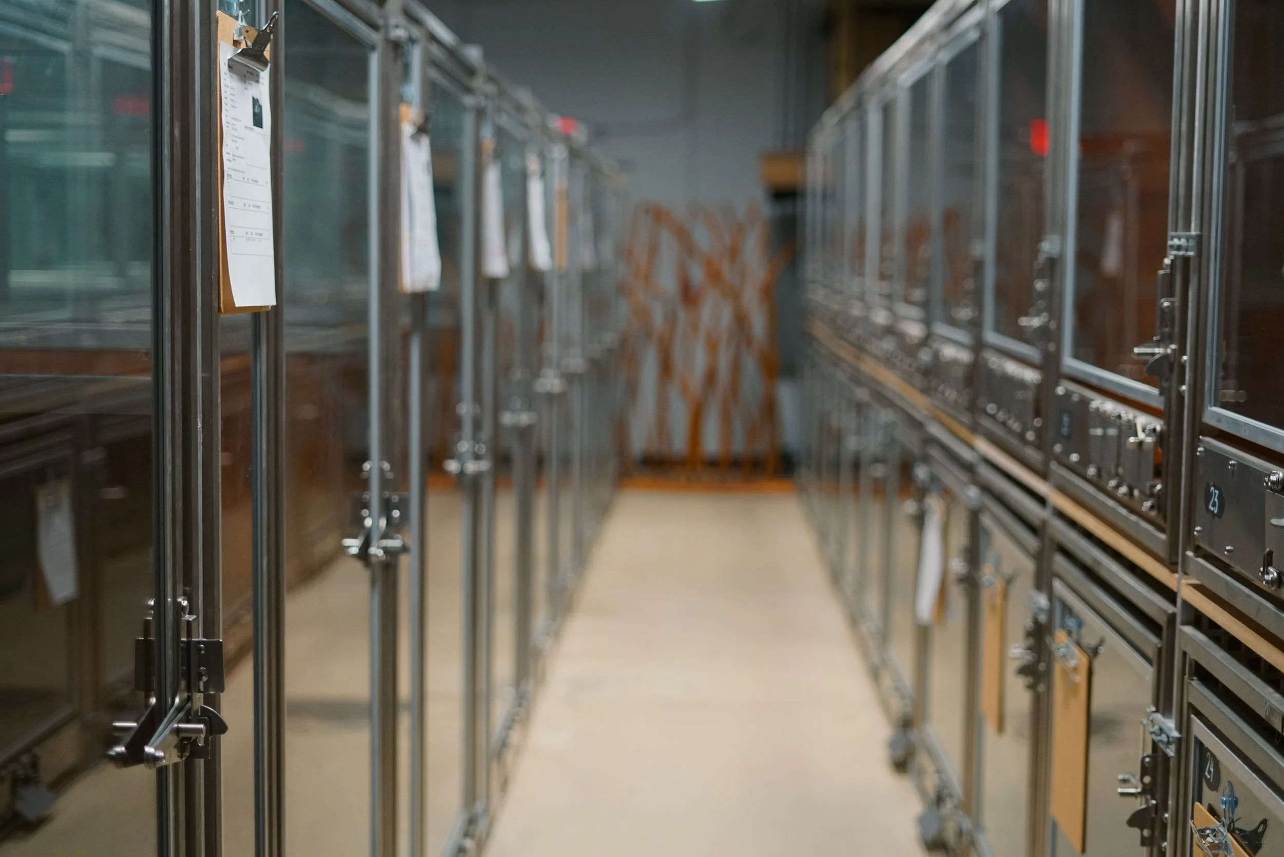 Empty metal lockers with clipboards hanging inside, in an industrial or storage area.