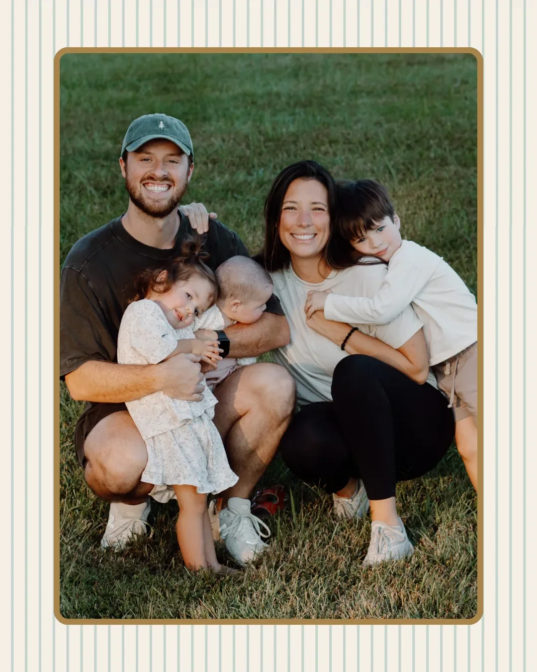 A family of five with three children, sitting on the grass outdoors, smiling at the camera during the daytime.
