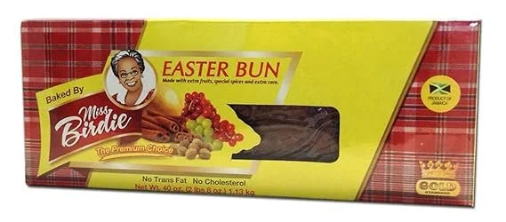 Box of Miss Bridie Easter Buns, a Jamaican pastry, with a decorated yellow and red packaging showing an illustration of a woman and images of fruit and spices.