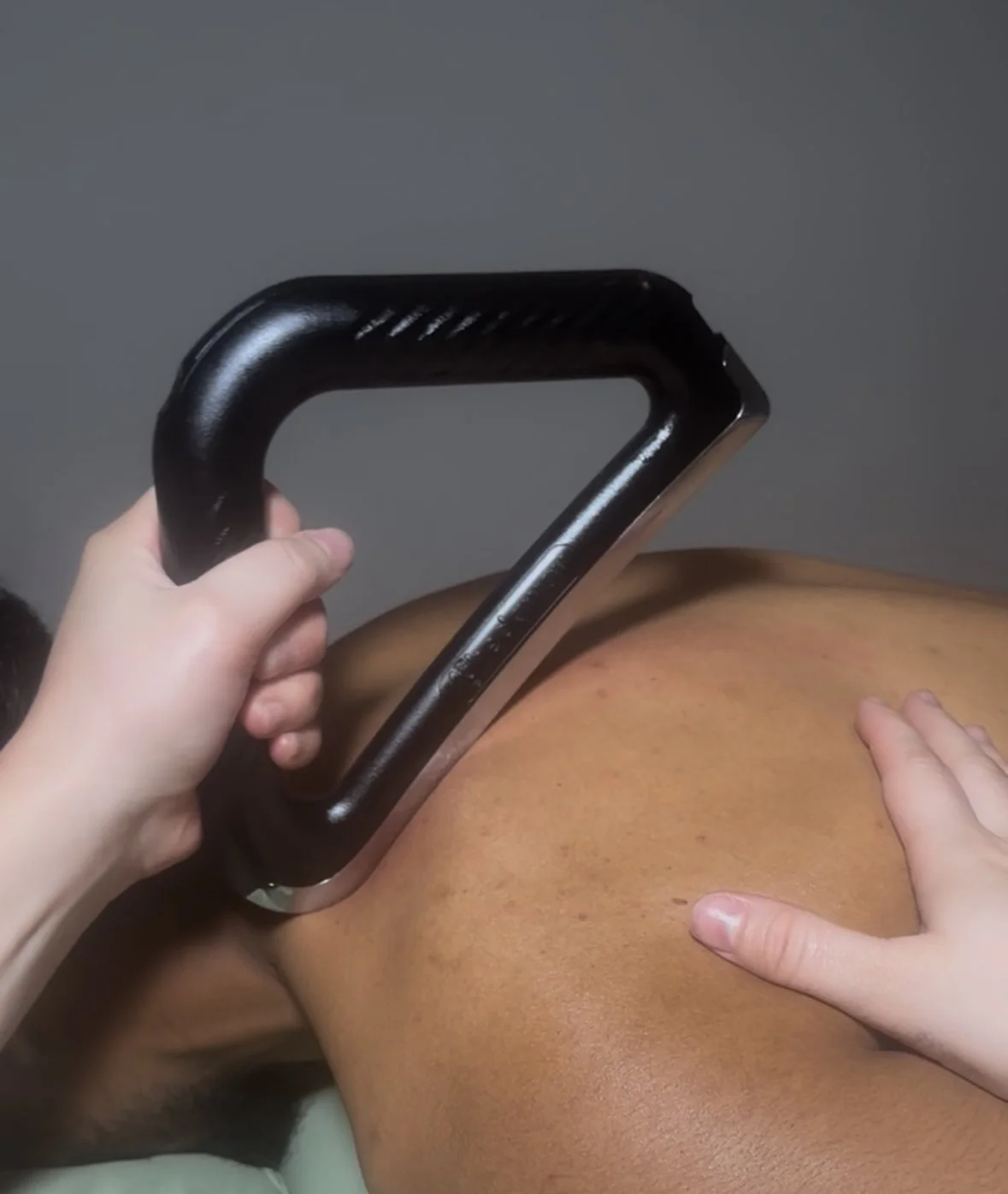 Person receiving a deep tissue massage on their back using a massage tool.