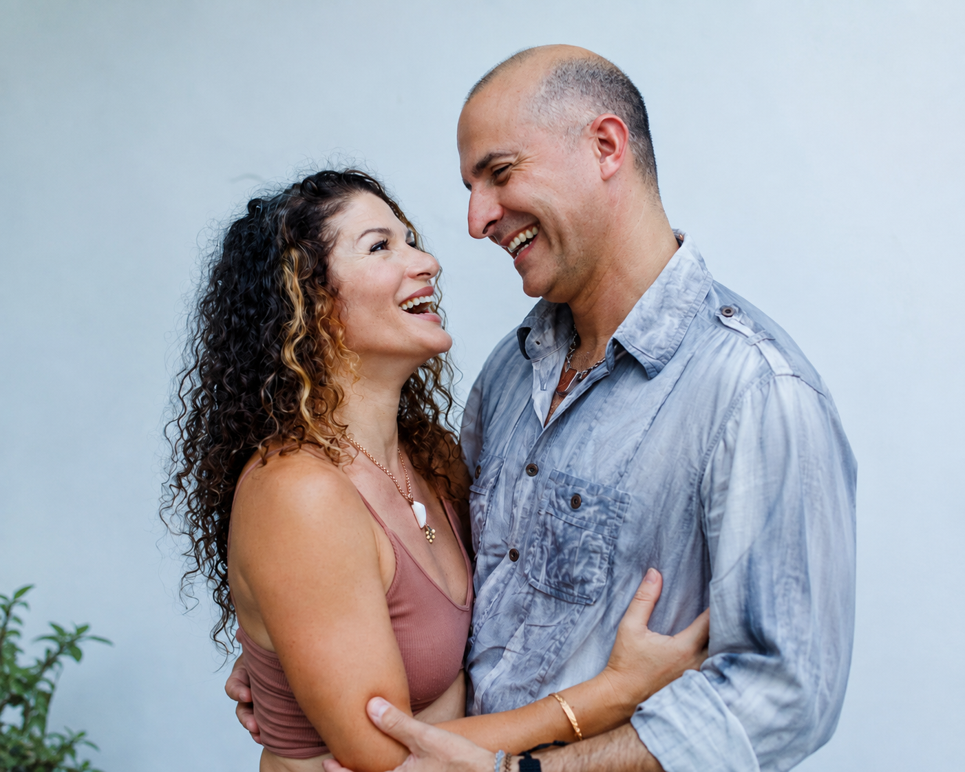Happy couple embracing and laughing together, looking lovingly at each other in a warm, natural moment.