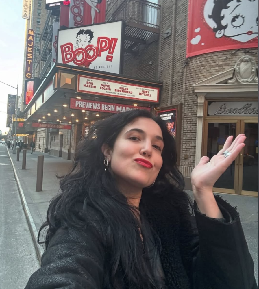 A photo of a woman with black hair standing in front of a broadway show called Betty Boop in NYC