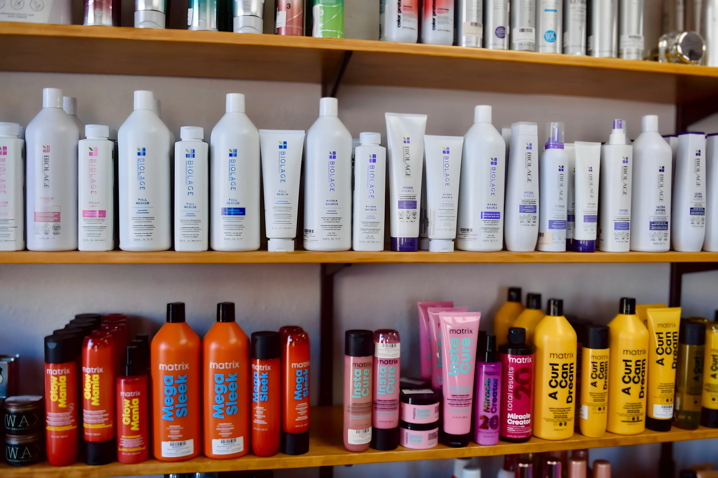 Shelves stocked with various hair care products, including shampoos and treatments, in bottles and tubes of different colors and sizes.