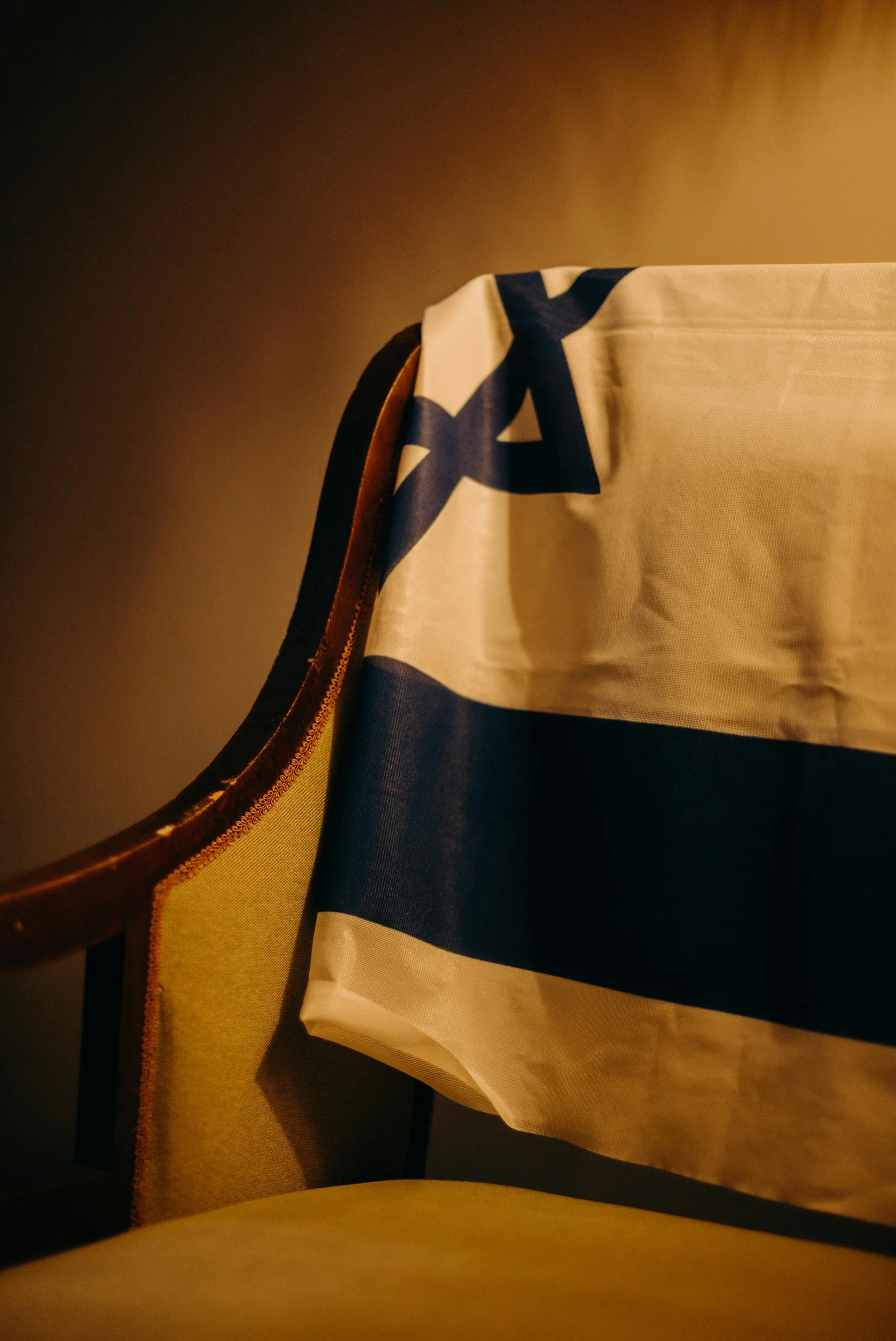 Part of a chair with a flag draped over it, showing a blue and white star pattern, in warm lighting.