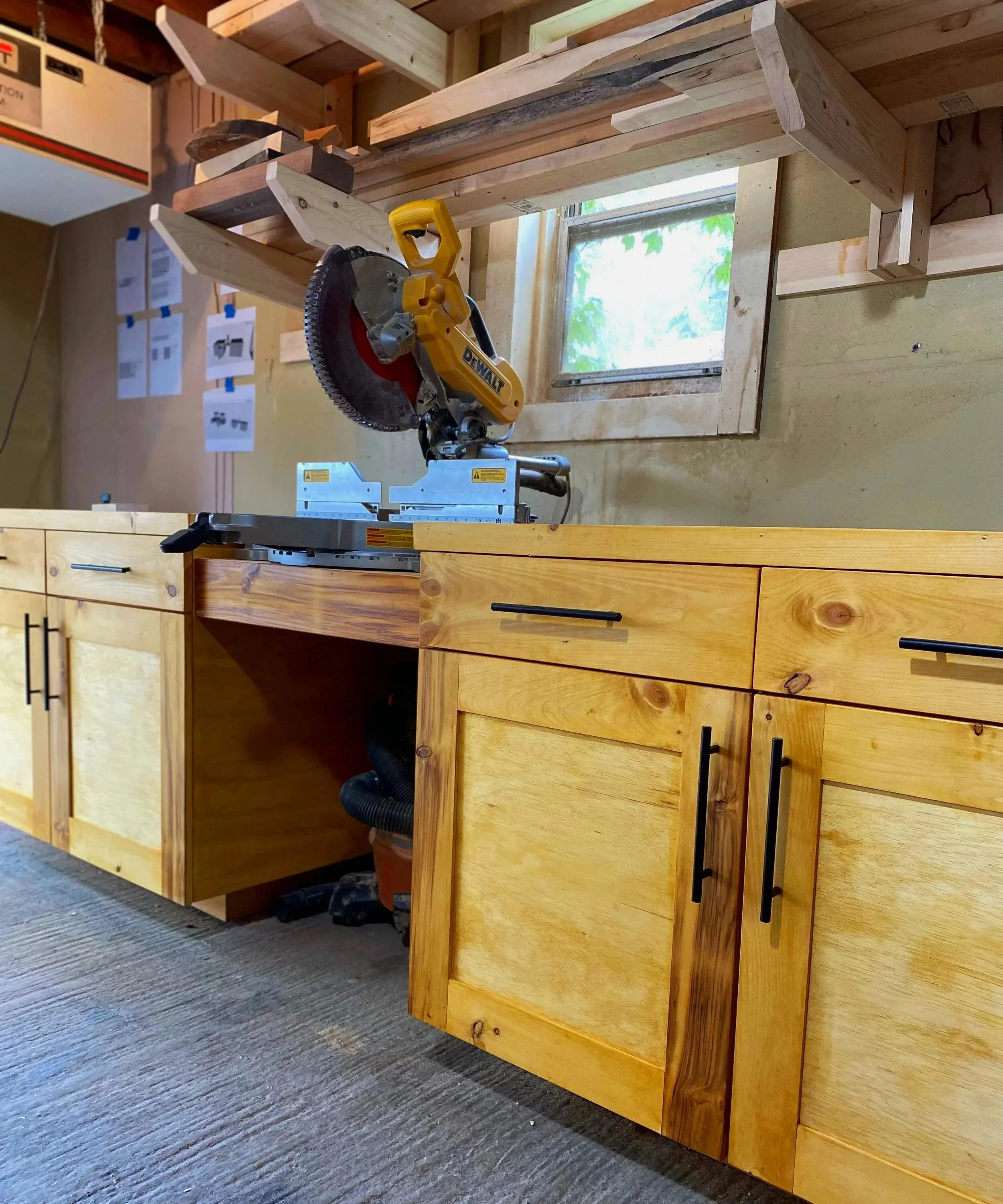 Custom-built wooden workbench with integrated cabinetry and a miter saw, showcasing Beverwyck Designs’ carpentry workspace.