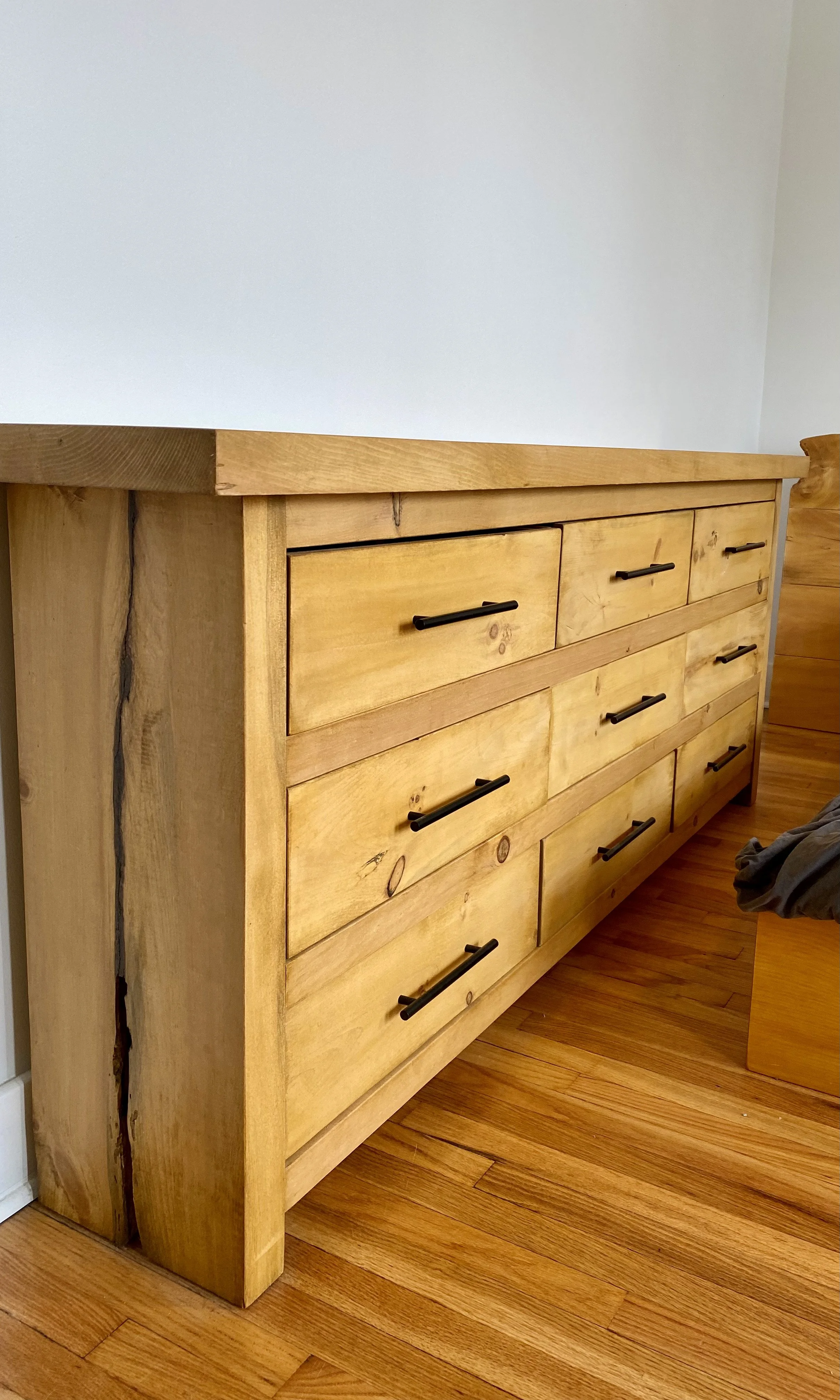 A wooden dresser with black handles, displaying a classic and modern design.