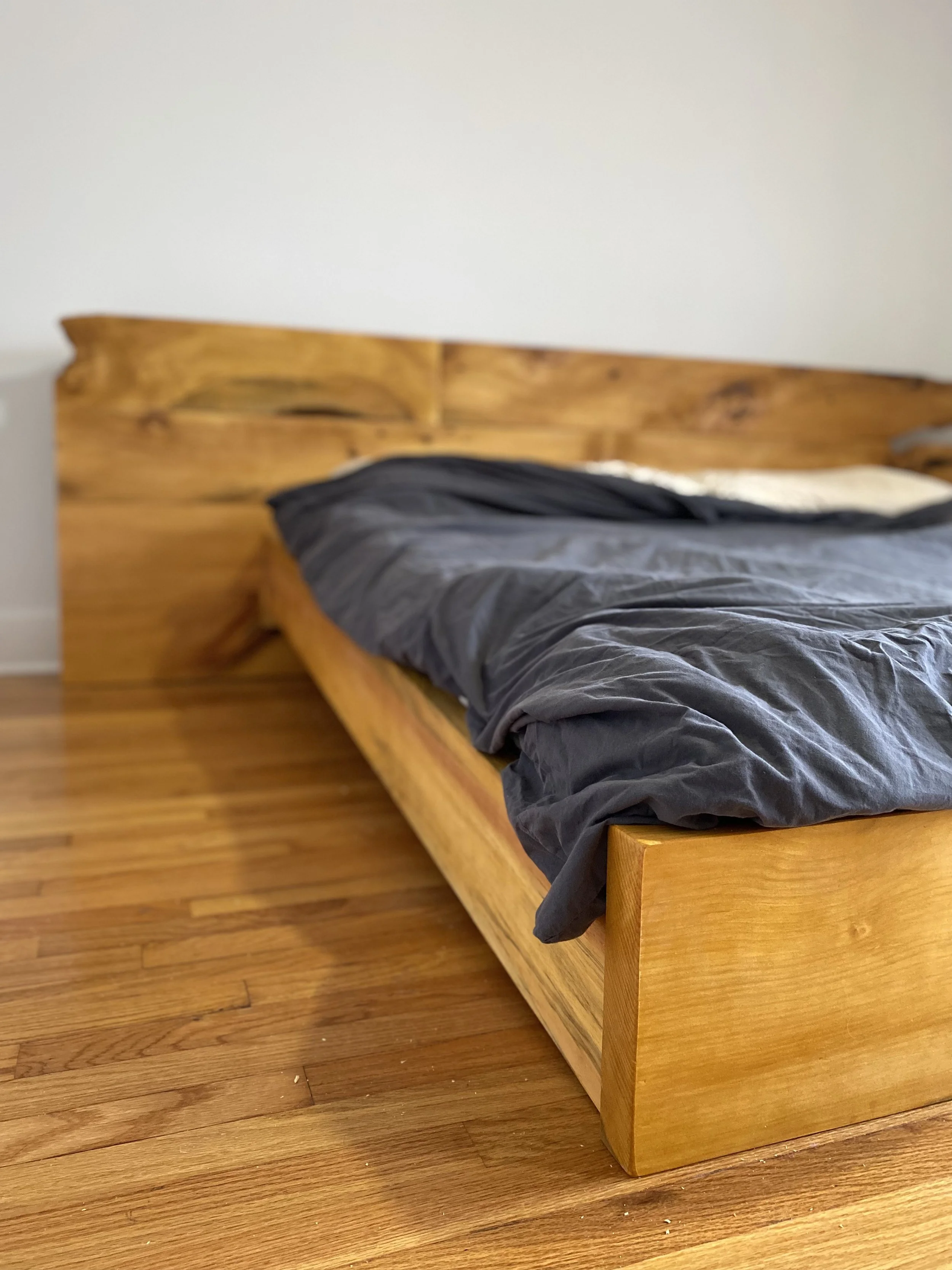 A custom oak bedframe with a stained wood finish.