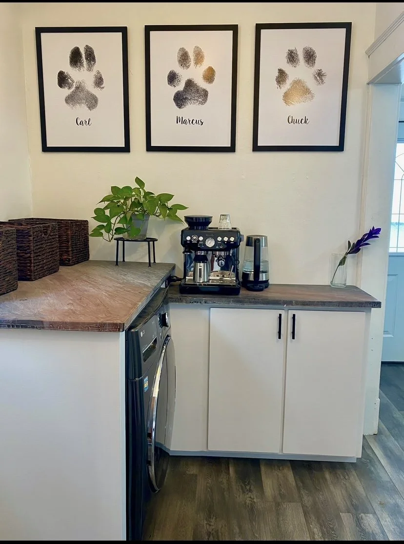 Custom built-in cabinetry with flat-panel doors and wood countertop, creating a compact coffee bar and laundry area with integrated washer and dryer, open shelving, and countertop appliance storage.