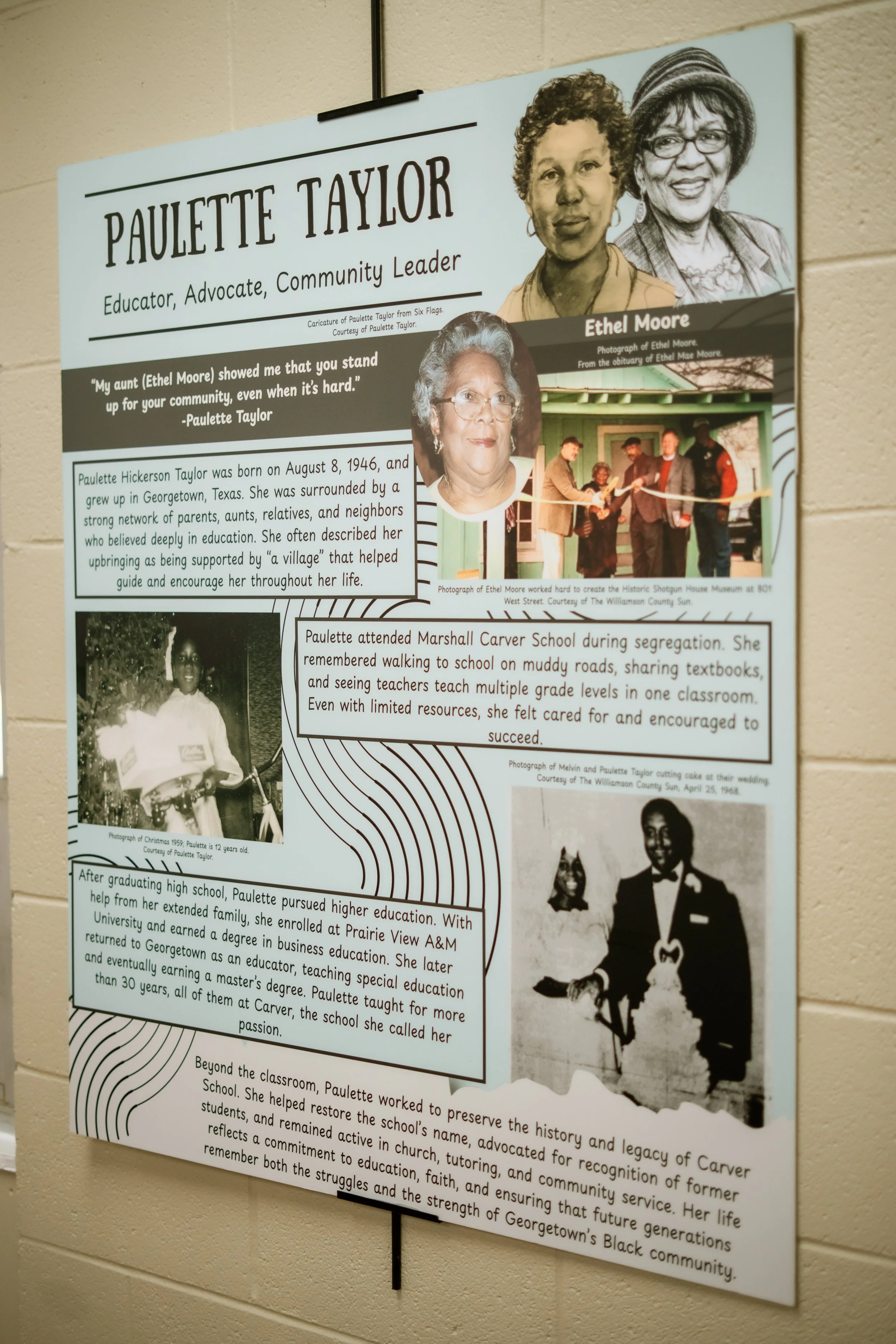 A wall-mounted poster featuring the biography of Paulette Taylor, including photographs of her and her family, with a quote from Paulette about community support. The poster outlines her early life, education, and community work, with a section on her efforts to preserve her family's history.