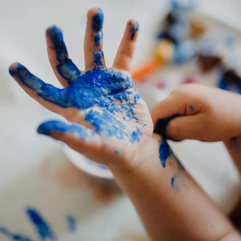 A child's hand covered with blue paint, being cleaned or wiped off.