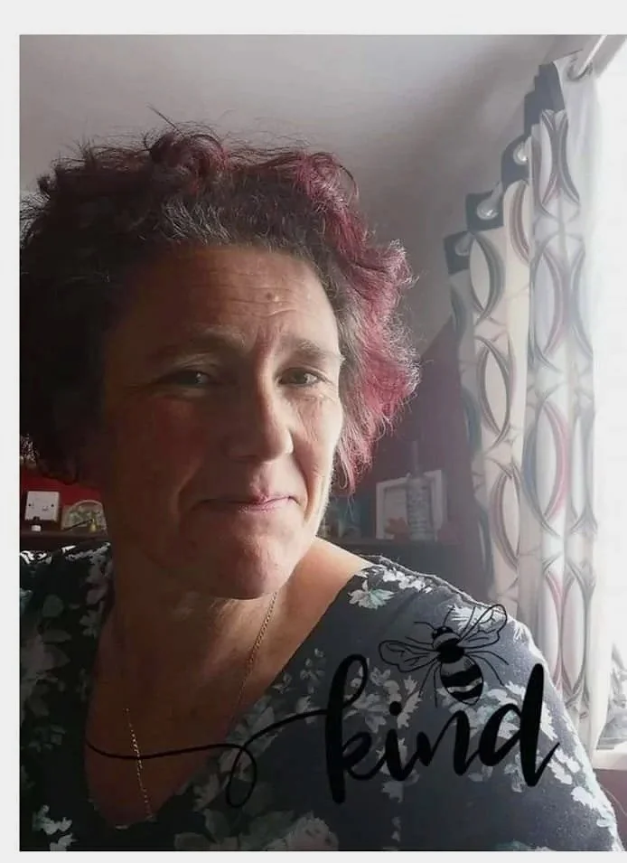 The image shows a lady looking into the camera lens, smiling. She has dark hair and a blue top.