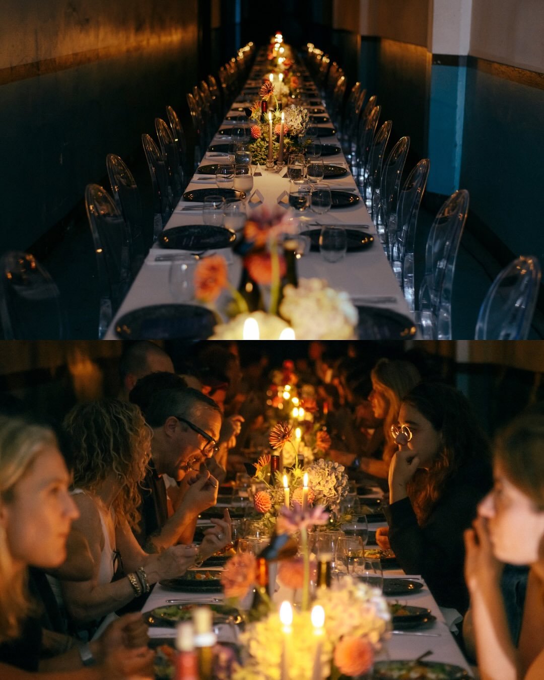 A long dinner table set for a formal event with floral centerpieces and candles, with guests dining in a dimly lit room.