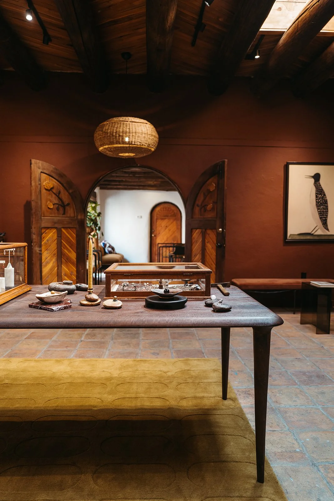 Interior of a rustic boutique with wooden doors, a decorative table with jewelry, and earthy decor elements.