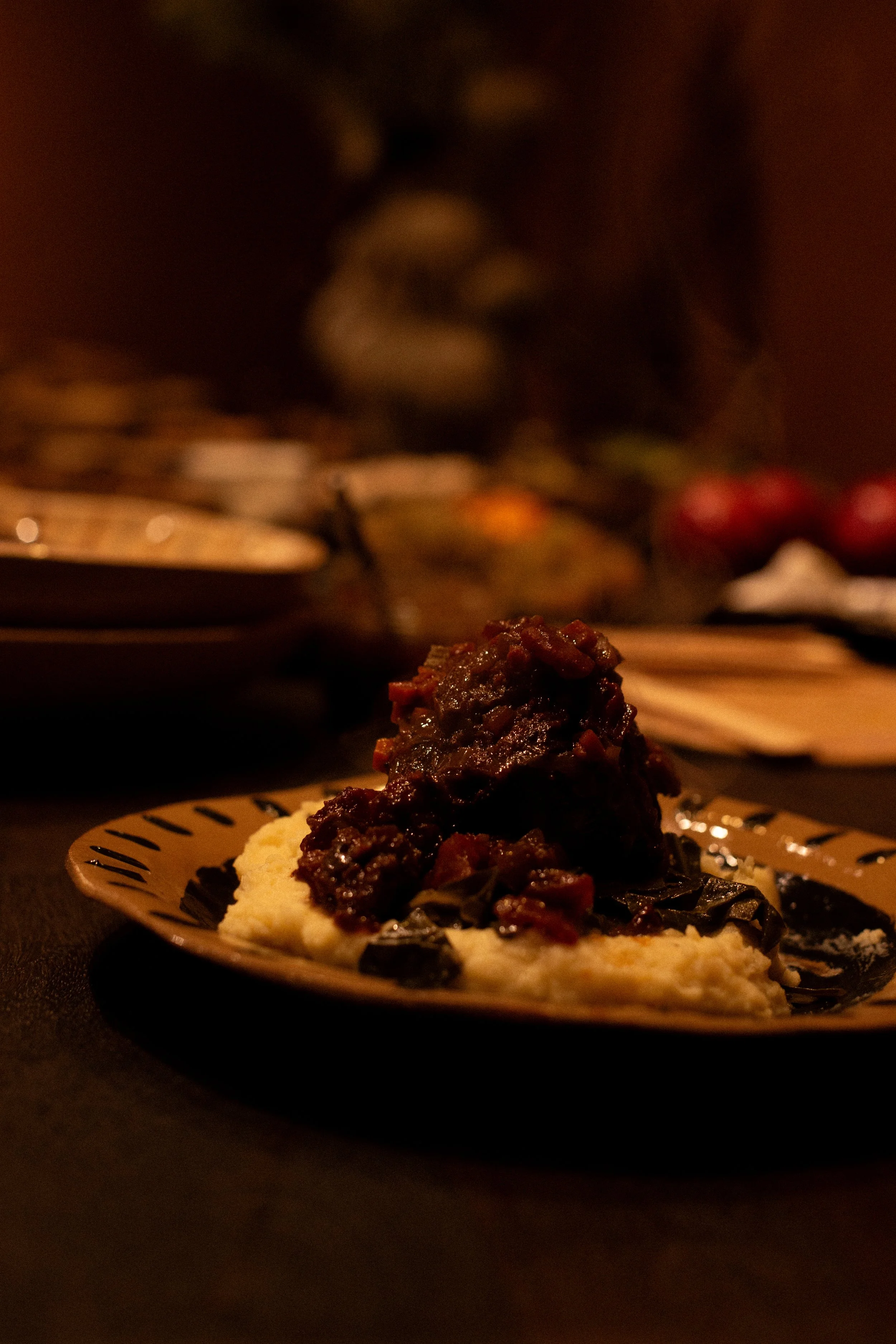 A plate of mashed potatoes topped with beef stew, with a dark background.