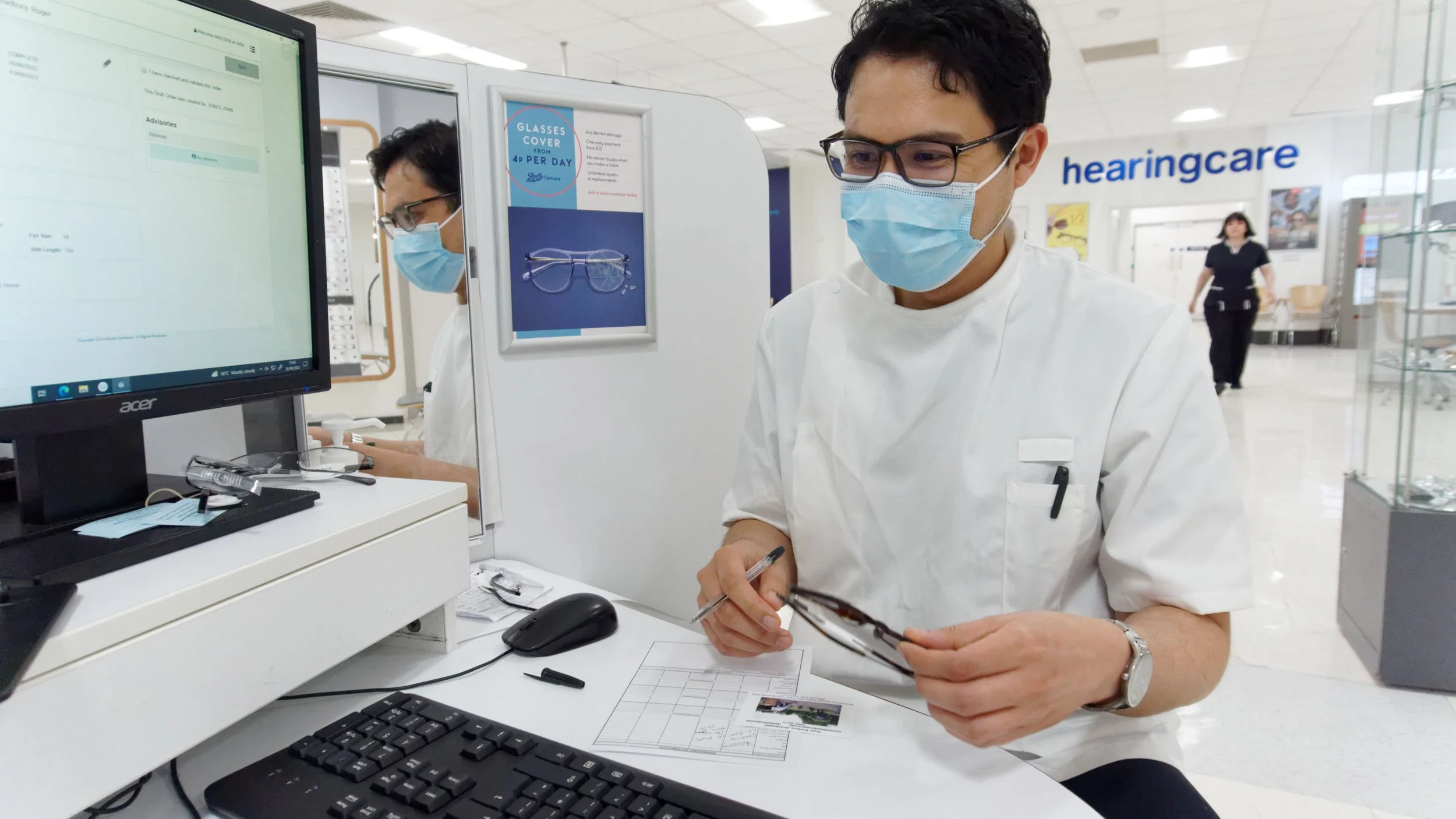 Assistant takes my order in Boots' Opticians. He wears a Covid mask.