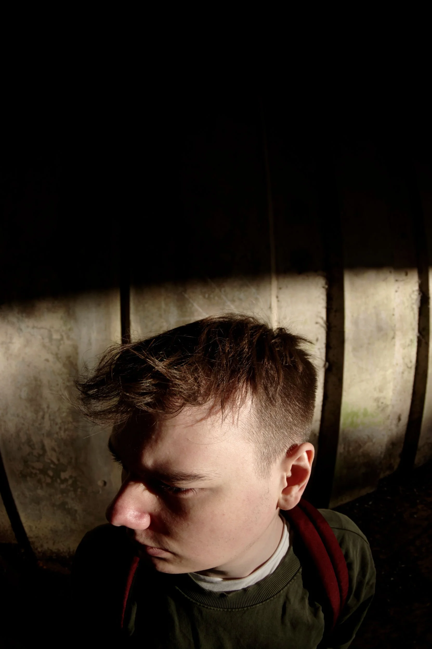 Fisheye lens photo of a man's head by a concrete wall.