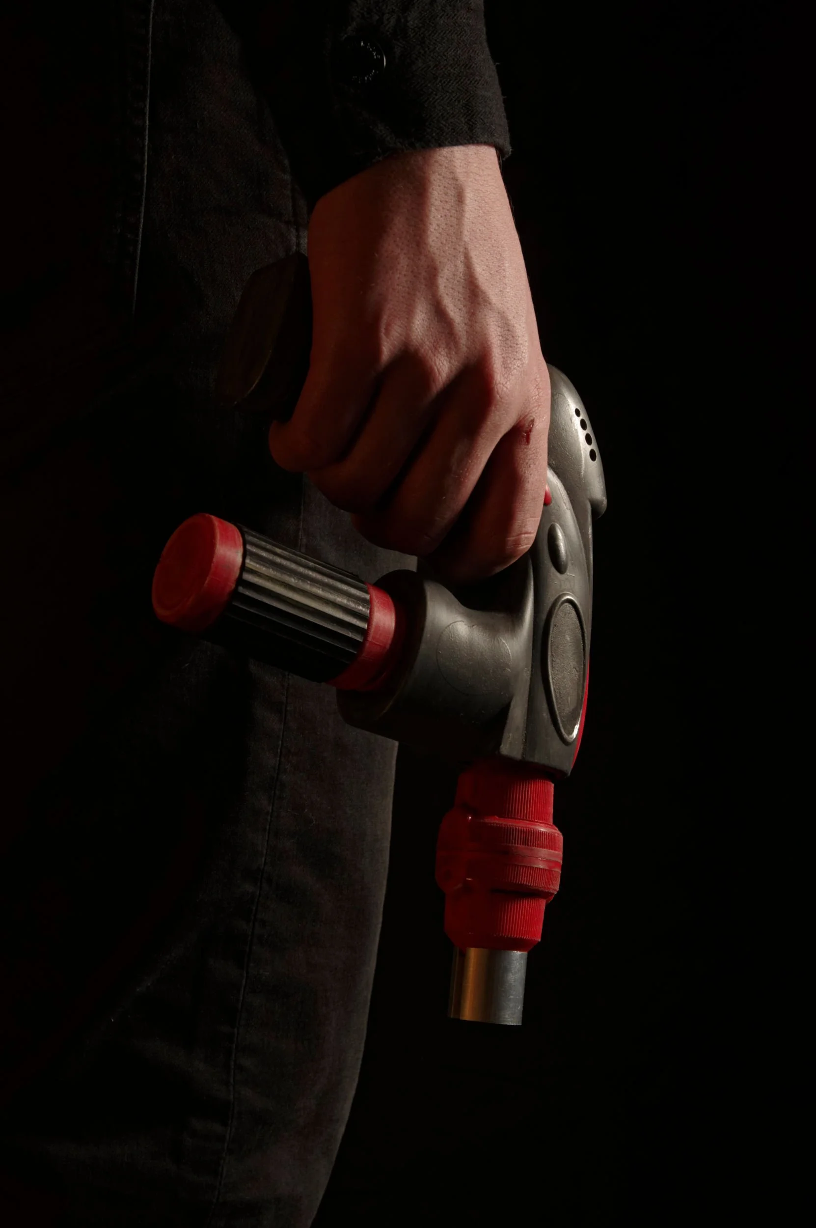 Man holds a blaster or ray-gun down by his leg.