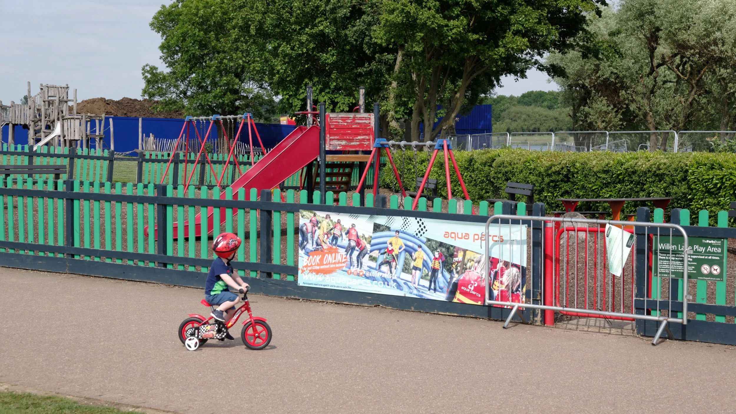 During lockdown, a child on a tricycle looks at a closed playground.