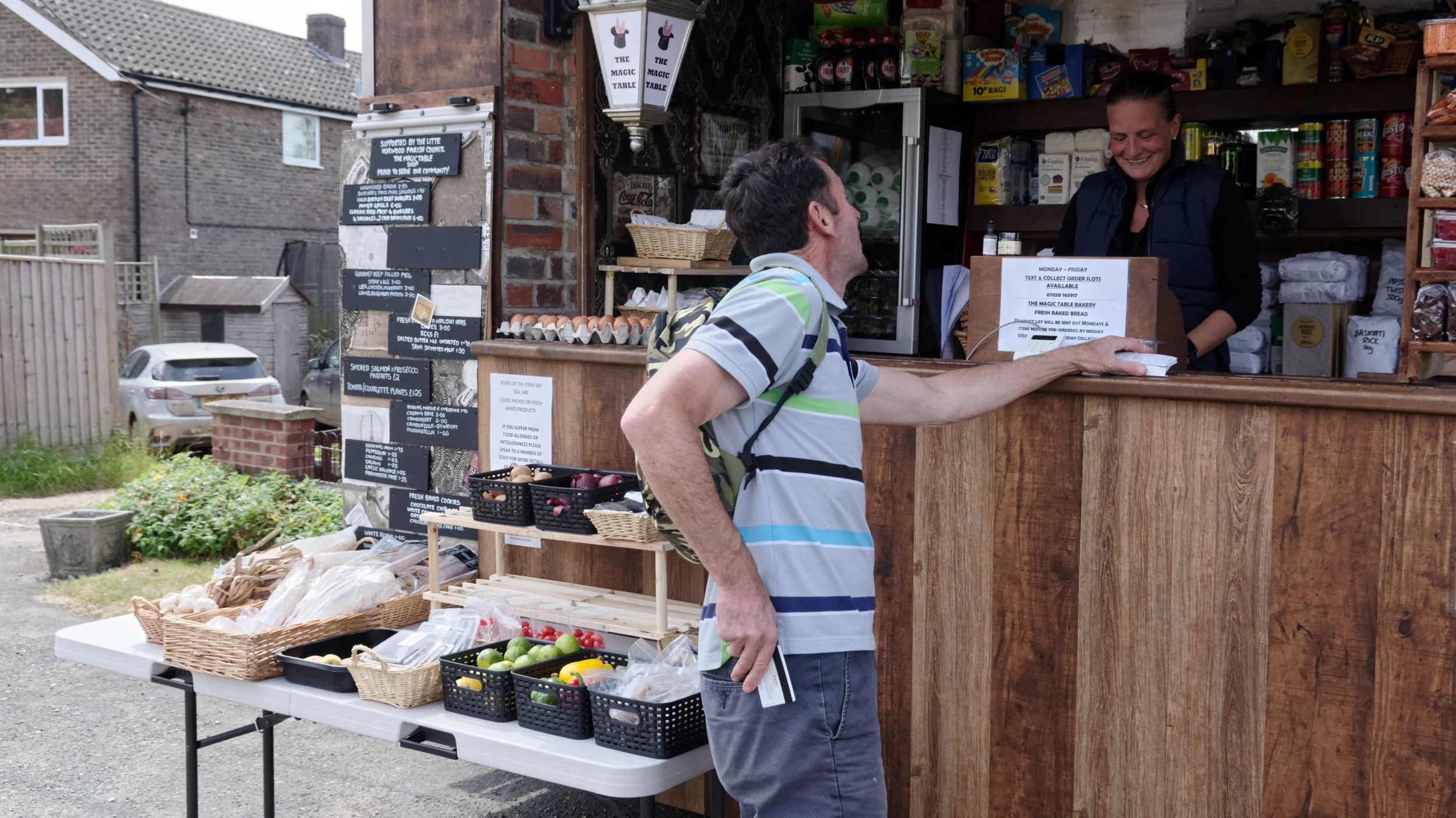 Customer keeps socially distanced from the owner at a temporary village shop.