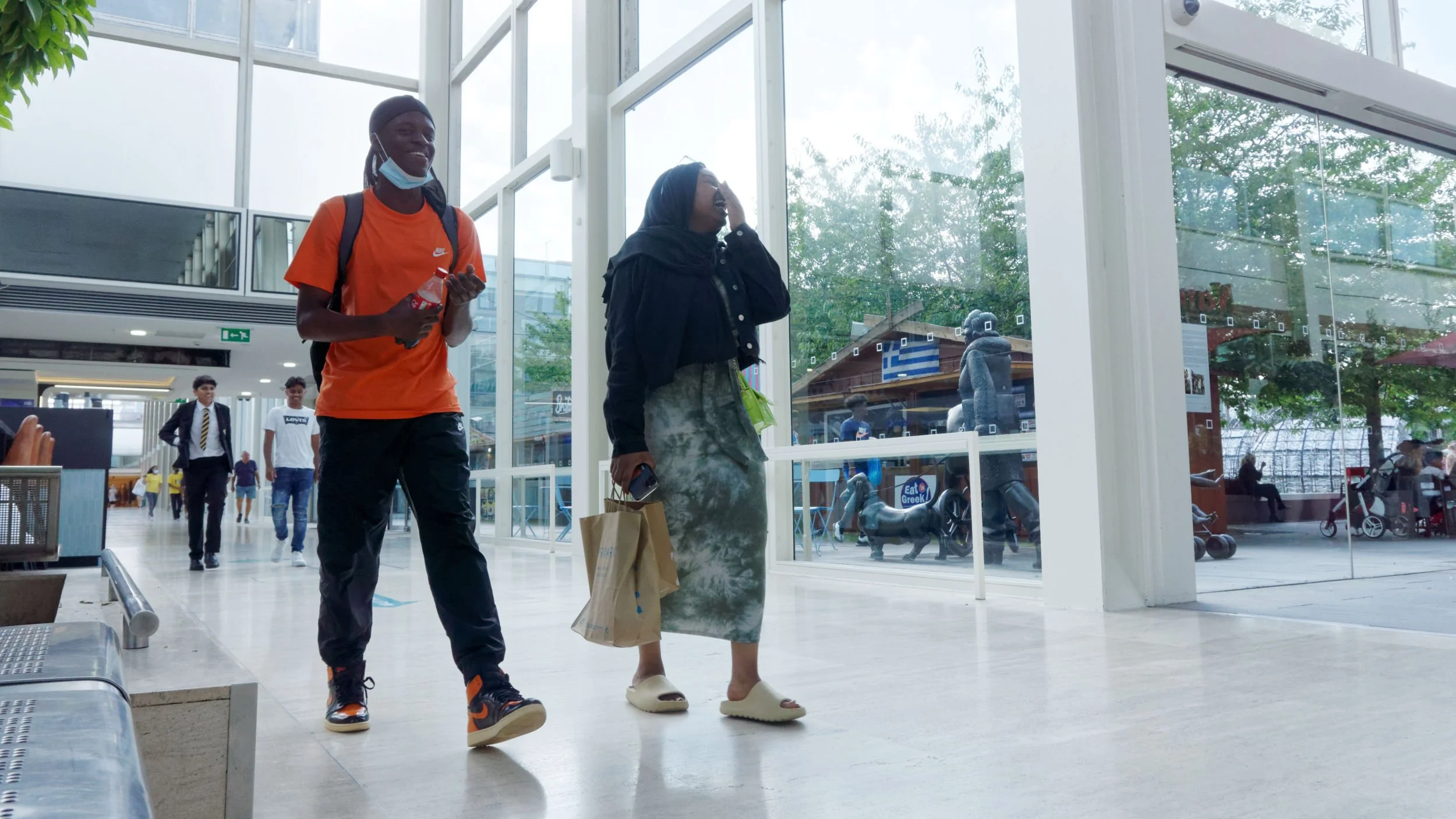 During lockdown a couple share a joke in a shopping centre.