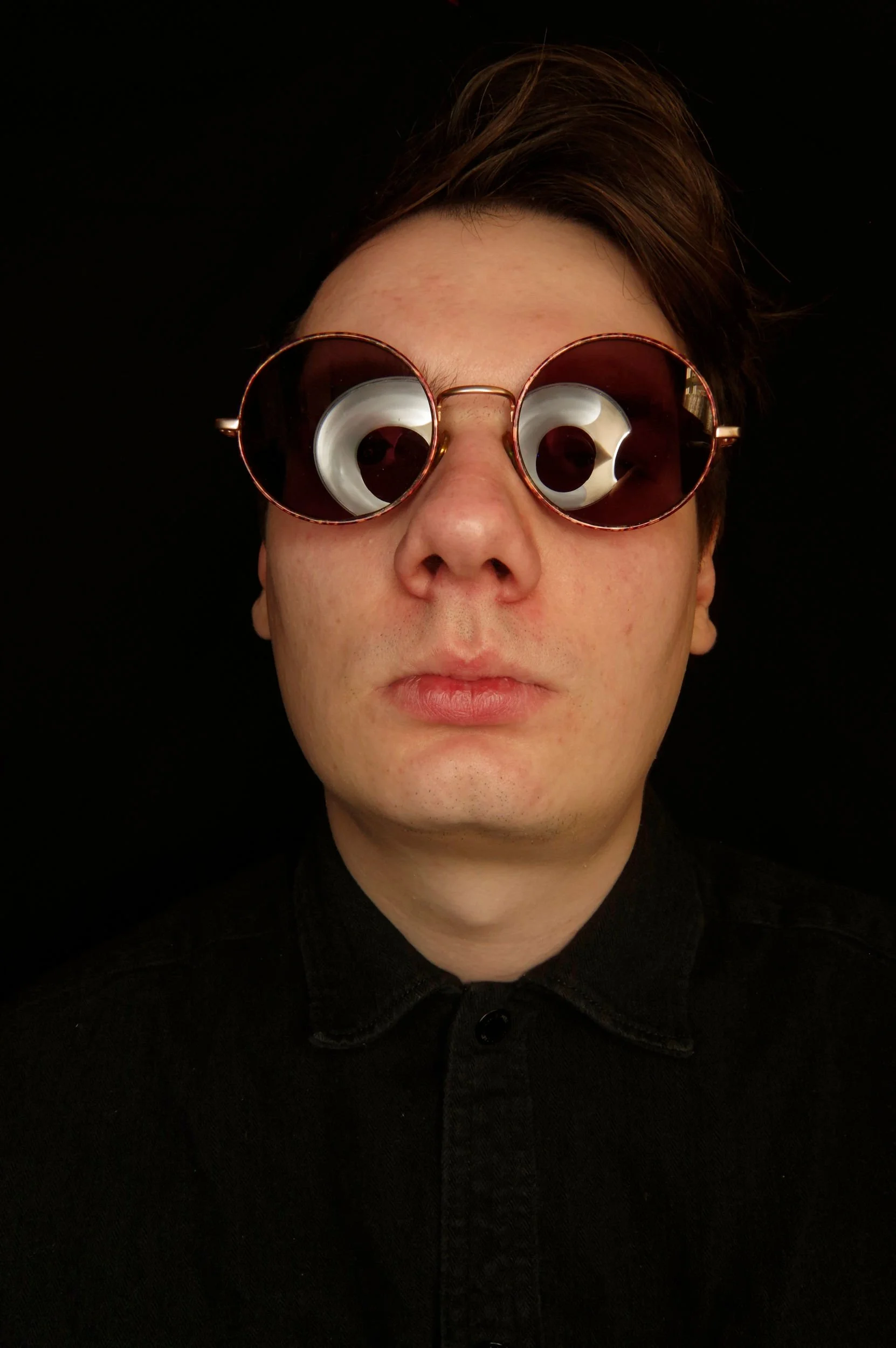 Man's head with dark sunglasses, on a black background. Fisheye lens shot.