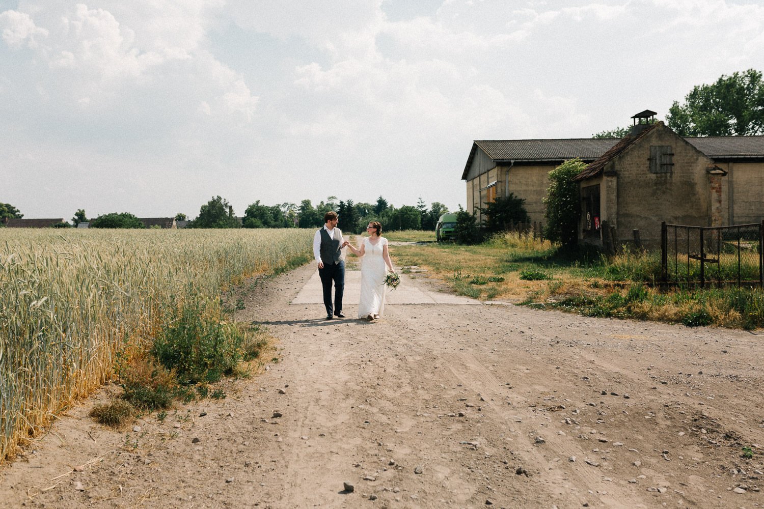 Brautpaar läuft Feldweg entlang