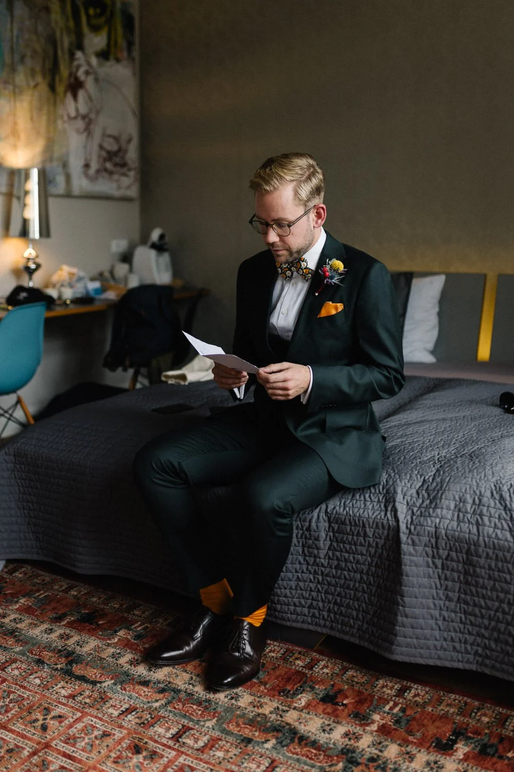 Bräutigam sitzt auf Bett und liest