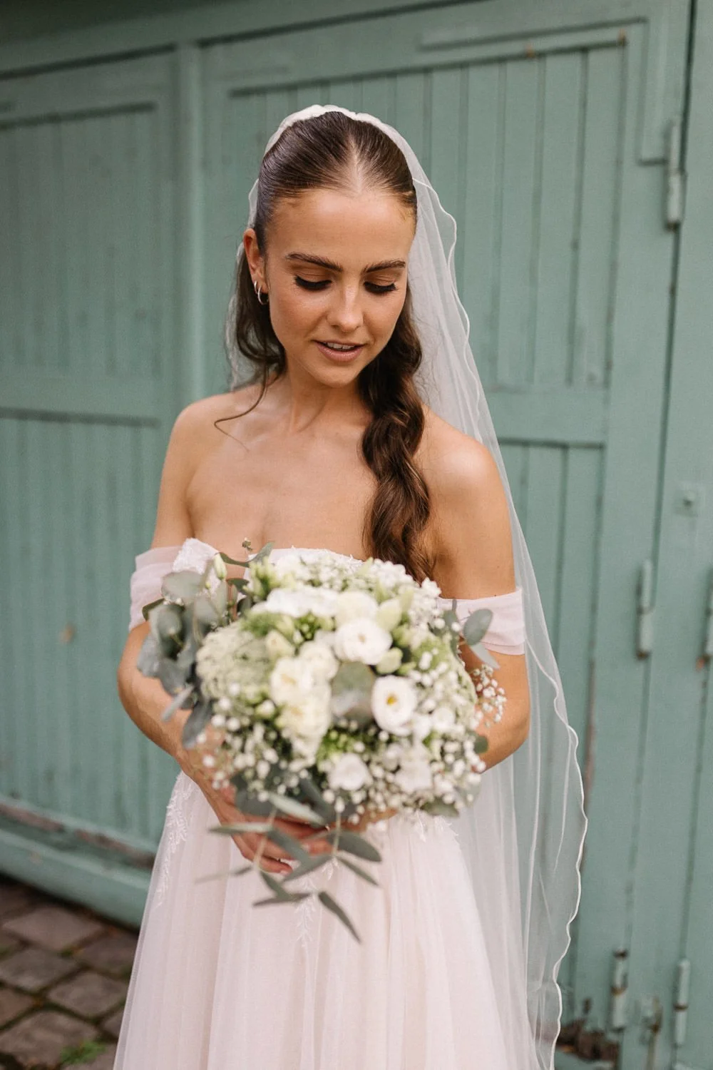 Portrait Braut mit Brautstrauß vor grüner Tür
