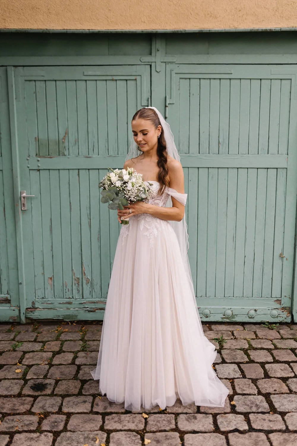 Portrait Braut mit Brautstrauß vor grüner Tür