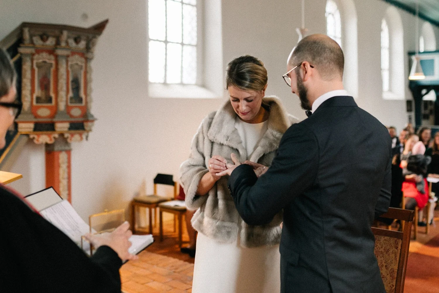 Brautpaar während Trauung, Braut steckt Bräutigam Ring an