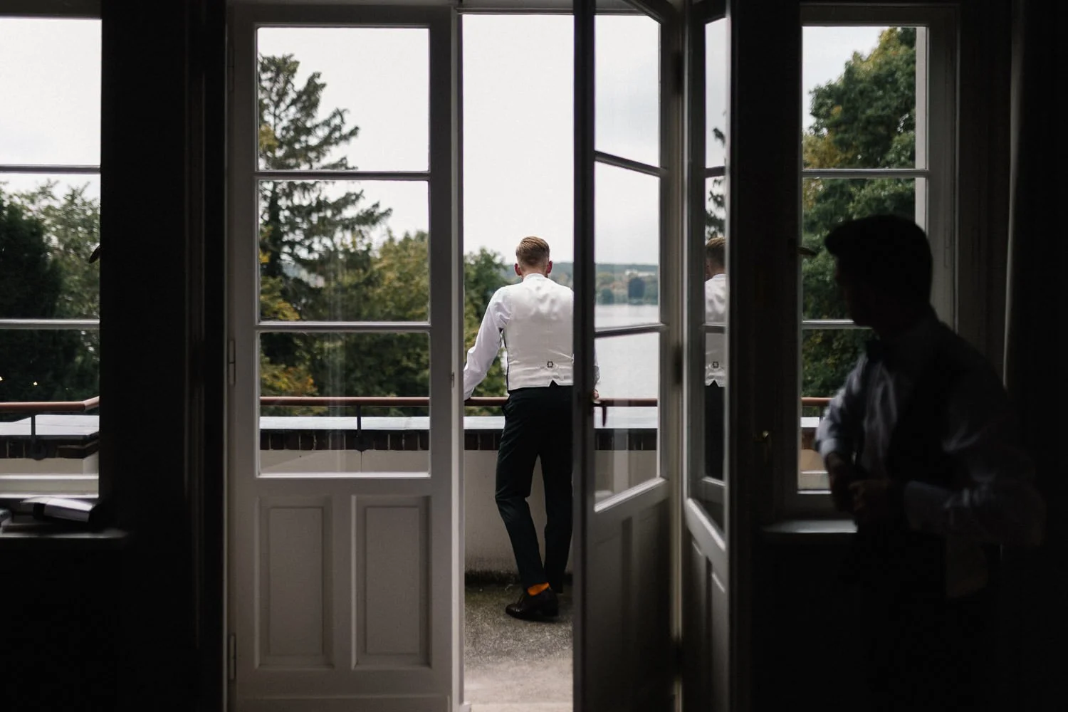 Blick aus Zimmer auf Terrasse, Bräutigam blickt in Garten