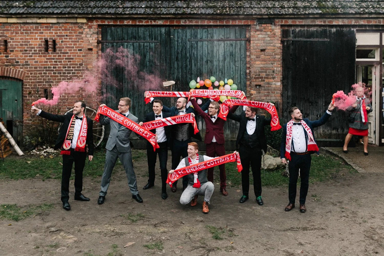Gruppenfoto männliche Hochzeitsgäste vor Scheune Haus am Bauernsee, Fußballfans Energie Cottbus Schals, Pyrotechnik