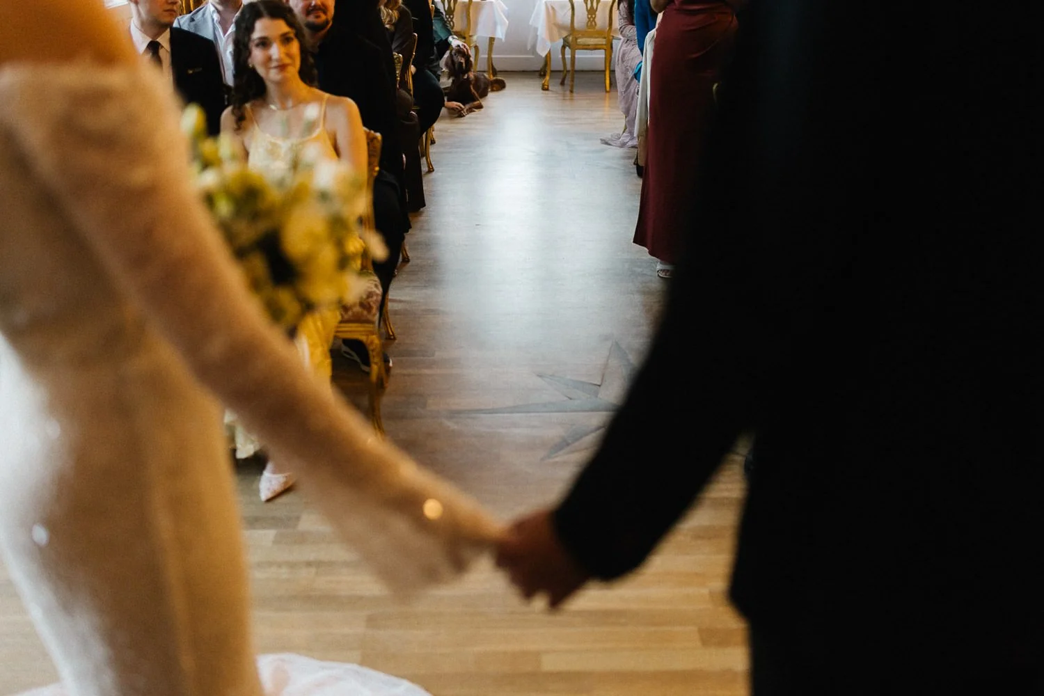 Blick durch das Brautpaar auf die sitzende Hochzeitsgesellschaft, am anderen Ende des Raums liegt ein Hund, Villa Bleichröder Usedom