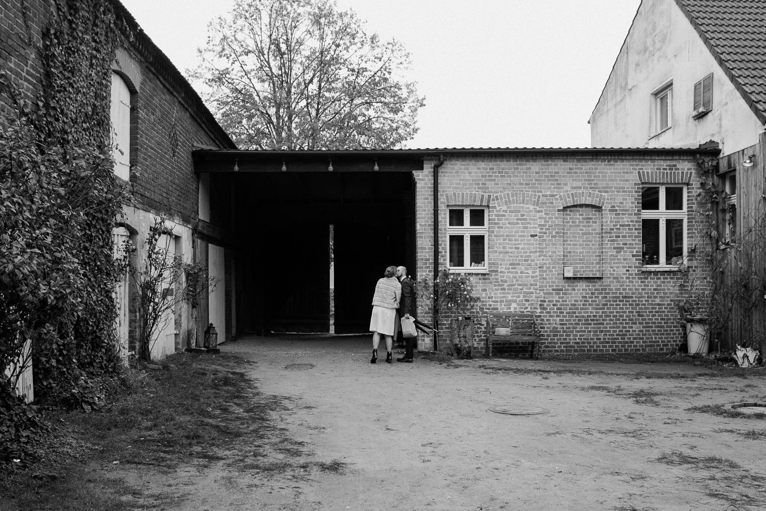 Blick auf Hof Haus am Bauernsee, Brautpaar küsst sich, Schwarz-weiß Foto