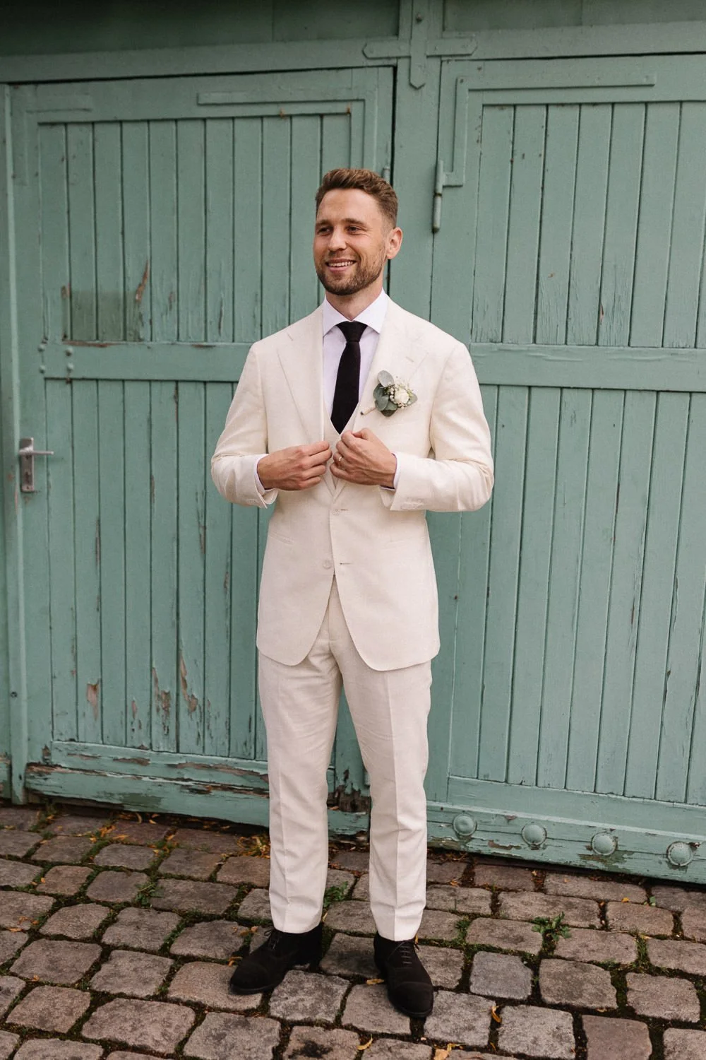 Portrait Bräutigam weißer Anzug vor grüner Tür