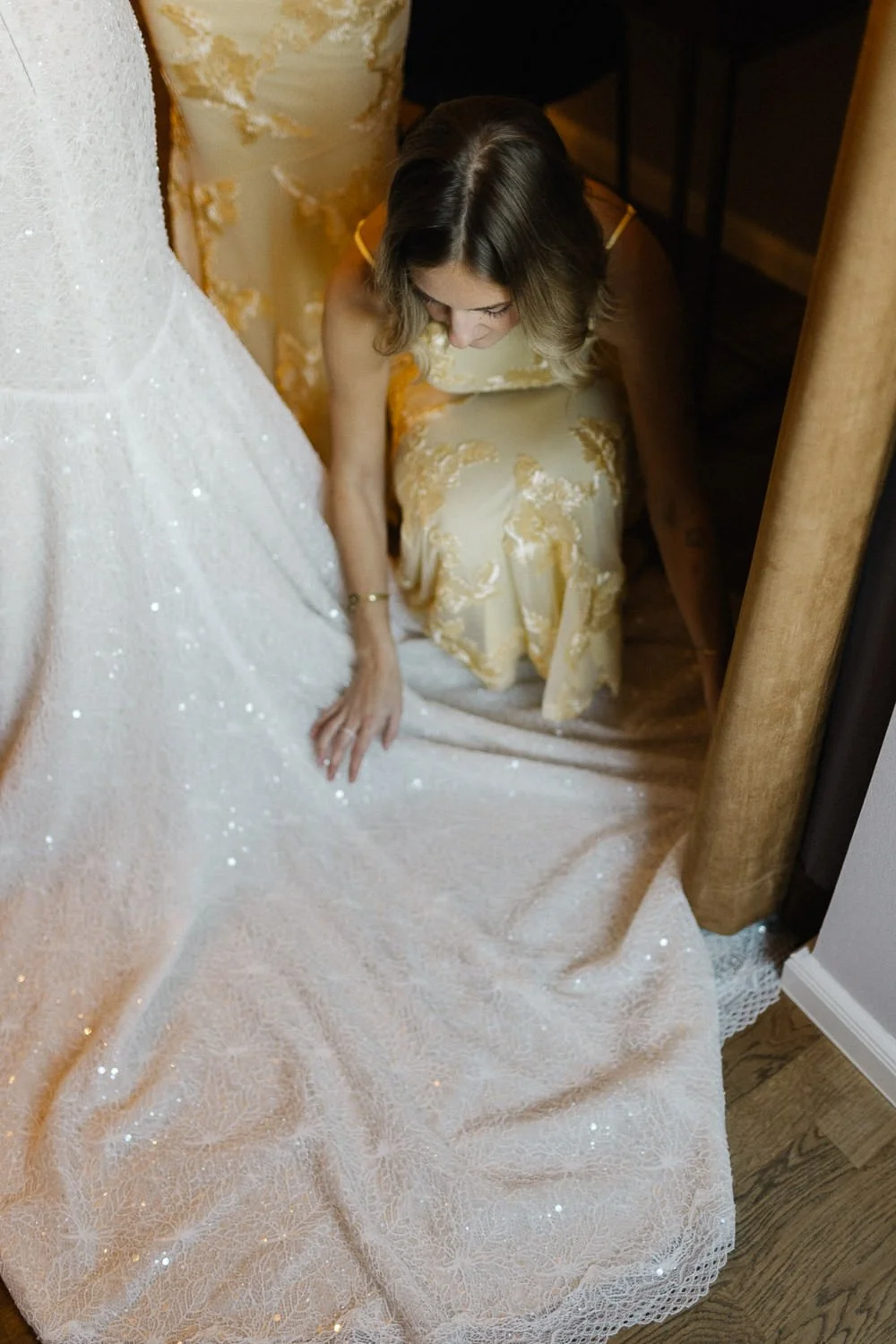 Trauzeugin in festlichem Kleid richtet Schleppe des Hochzeitskleides