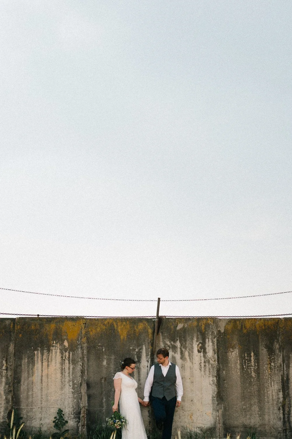 Brautpaar steht vor Mauer