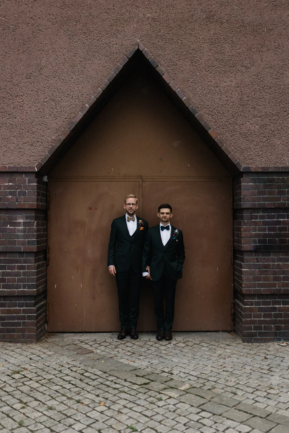 LGBTQ Hochzeitspaar steht vor brauner Tür