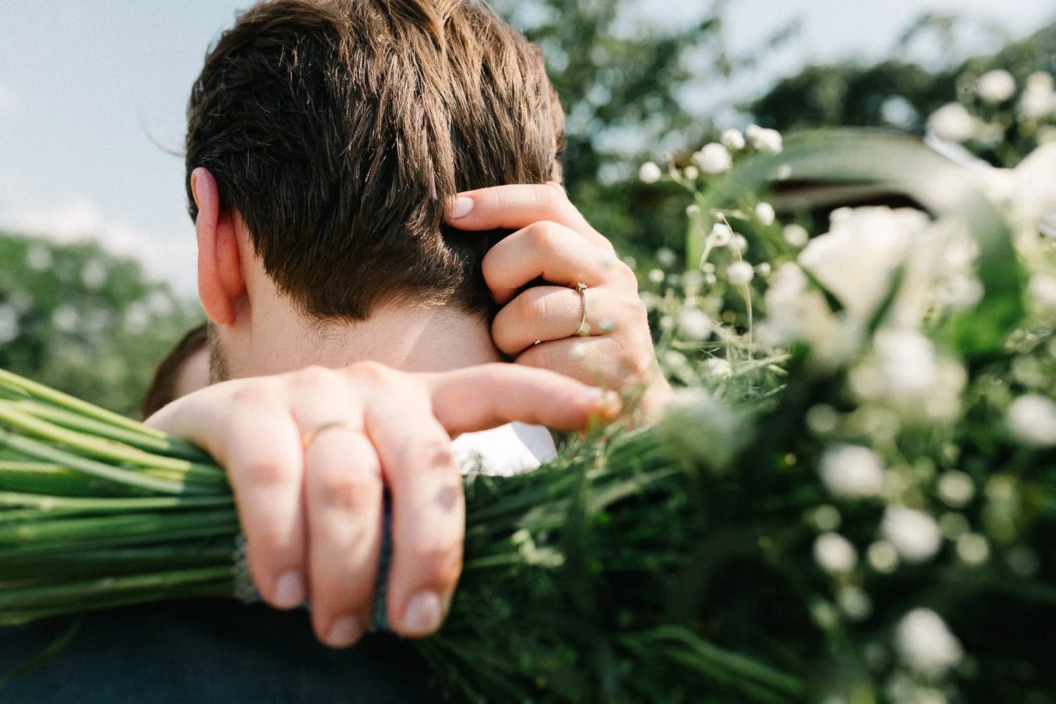 Detailaufnahme, Hand hält Brautstrauß, andere Hand streichelt Kopf