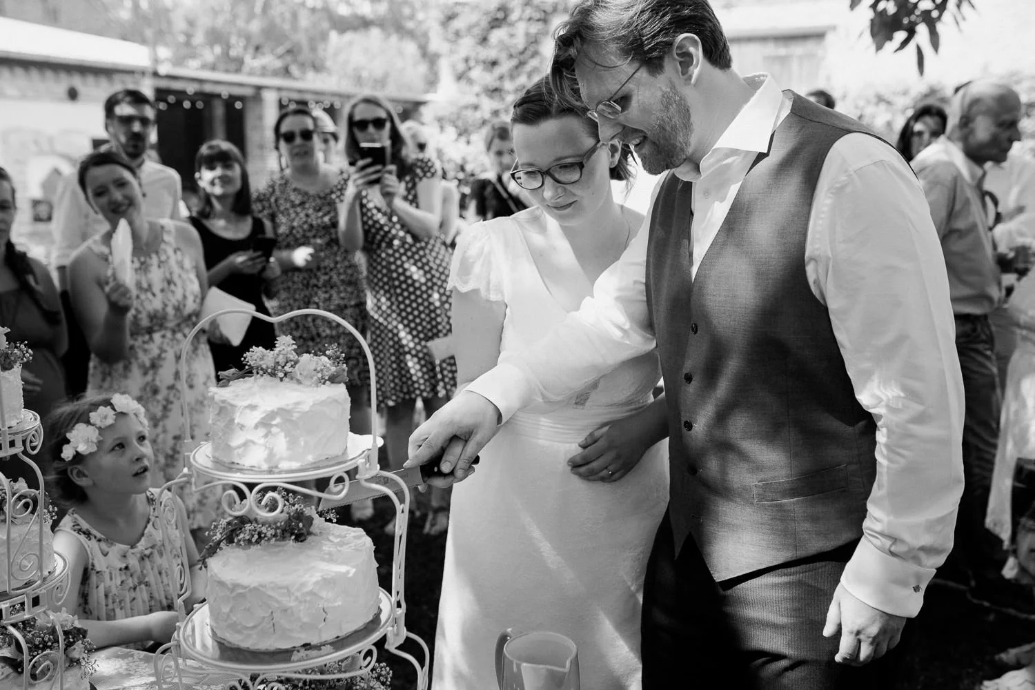 Brautpaar schneidet Hochzeitstorte an, Schwarz-weiß Foto