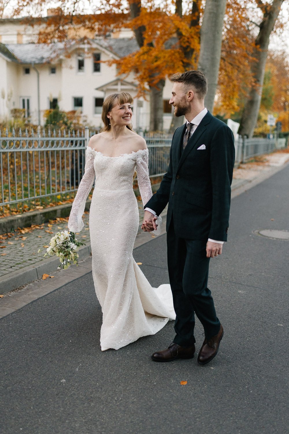 Paarshooting am Hochzeitstag, Brautpaar läuft Straße entlang, Herbstlaub an den Bäumen, Heringsdorf Usedom
