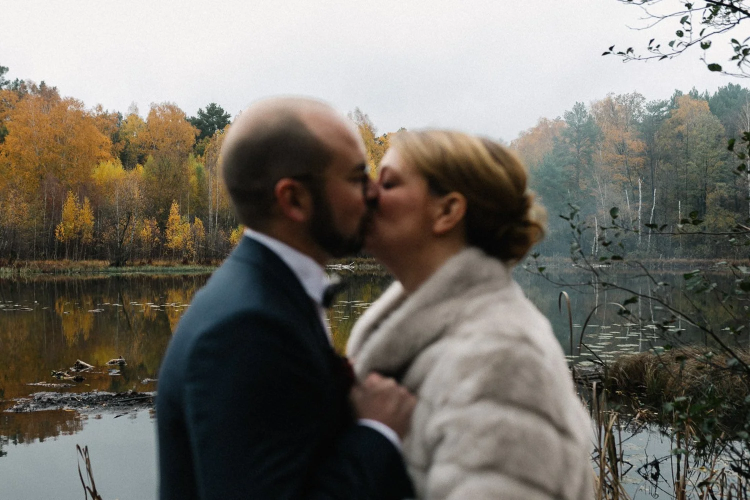 Brautpaar unscharf küsst sich, See im Hintergrund, Herbstfarben