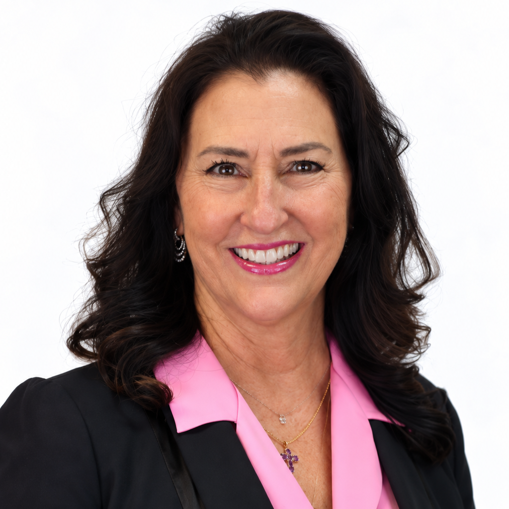 Close-up of a smiling woman with dark hair and brown eyes, wearing a pink top and earrings, against a neutral gray background.