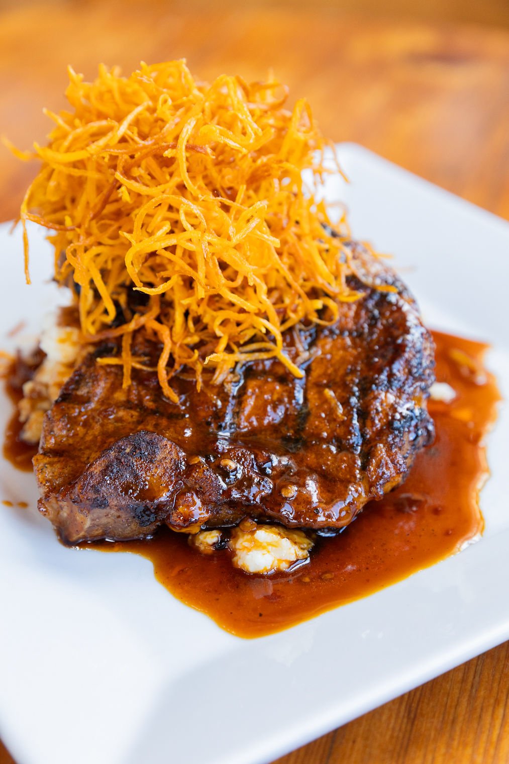 A plate of food with a piece of grilled meat topped with shredded cheese and a side of sauce.