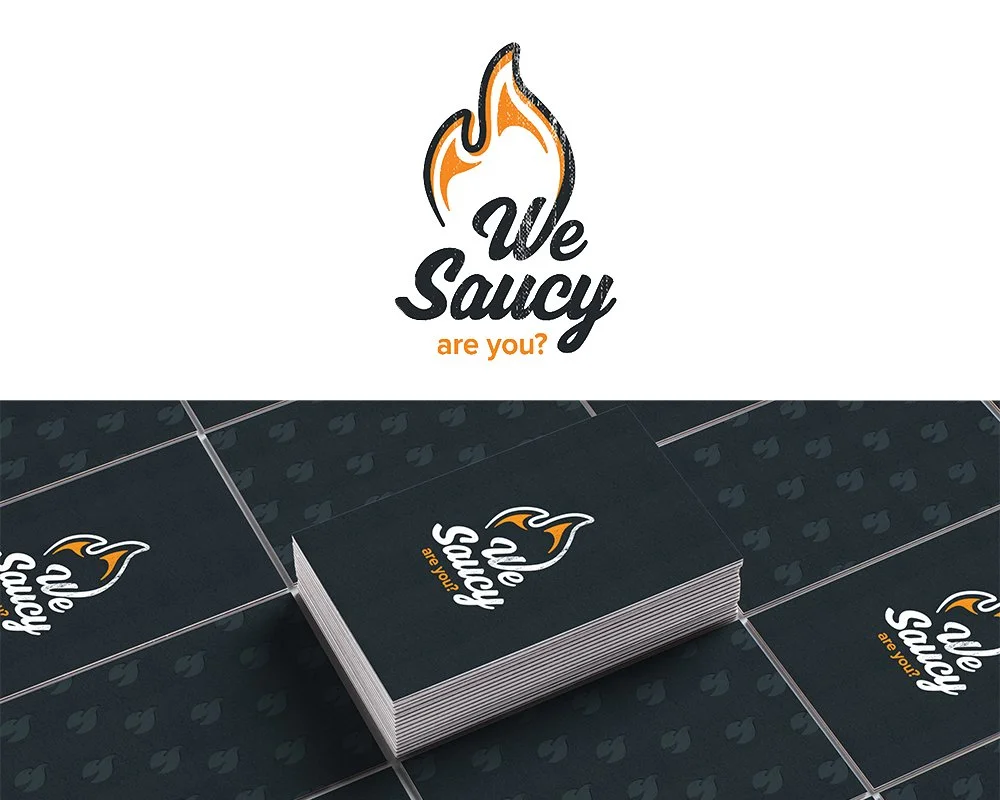 A logo for a brand or company named 'We Saucy,' featuring a flame design above the text. Below the logo, there are stacks of business cards displaying the same logo and tagline, with a dark background and a subtle pattern.