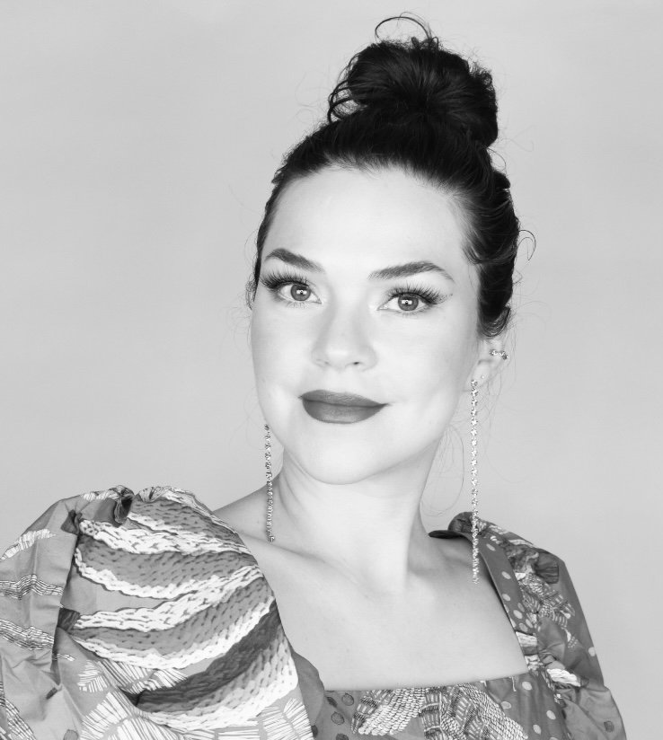 Black and white portrait of a woman with her hair in a bun, wearing earrings and a patterned dress.